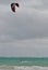 Kitesurfing man with kite in sky on kiteboard in sea riding waves with water splash. Water sports. Hobby and fun in