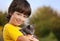 Kitten on arm of the boy outdoors, child huge his love pet