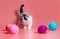 Kitten with multi-colored balls of woolen threads on a pink background