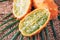 Kiwano or african horned melon with palm leaves on rattan background. Cutted hedged gourd, african horned cucumber, english tomato