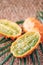 Kiwano or african horned melon with palm leaves on rattan background. Cutted hedged gourd, african horned cucumber, english tomato