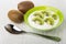 Kiwi, bowl with cottage cheese and slices of kiwi fruits, spoon on table