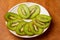 Kiwi single whole and sliced in pieces in a white plate and on a wooden board