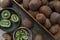 Kiwifruits and slices of kiwi in a wooden box and a bowl.