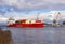 Klaipeda, Lithuania - 02 06 21: huge red cargo container ship on winter Curonian lagoon in front of terminal industrial