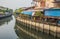 A klong or river channel with fishing boats, buildings and house fronts in Thailand