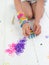 kneeling childs hands making a multicoloured elastic band bracelet on a band loom