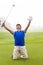 Kneeling golfer cheering on putting green