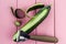 Knife for cleaning vegetables and fruits with cucumber with peeled skin on a pink background