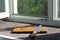 Knife and cutting board with crumbs on the windowsill, creative still life with hard light, empty and minimalism concept