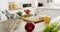 Knife, cutting board, vegetables and tablet on counter in sunny kitchen, slow motion