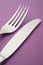 Knife and fork detail over a purple background. Cutlery