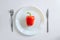 Knife, fork and red pepper, paprica on a white plate on a white background, top view