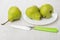 Knife, green pears in glass plate and on wooden table