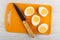 Knife, halves of peeled eggs on cutting board on wooden table. Top view