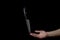 Knife on the hand on a dark background. The knife balances on a finger against a black background.