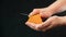A knife in her hand, she slices in an old piece of cheese, called mimolette, on a black background