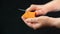 A knife in her hand, she slices in an old piece of cheese, called mimolette, on a black background