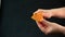 A knife in her hand, she slices in an old piece of cheese, called mimolette, on a black background