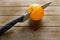 Knife slicing through an orange of the kitchen table before breakfast.