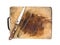 Knife and tongs on a wooden chopping board on white bac