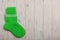 Knit green wool socks on light wooden background.