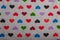 Knit grey fabric texture with multicolored hearts print, background or backdrop. Textile, scarf or sweater textured surface