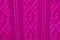 Knit texture of pink wool knitted fabric with cable pattern as background. Magenta texture