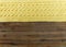 Knited yellow fabric.braid pattern on the wooden background.