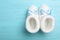 Knitted child`s booties on blue wooden background, top view