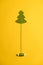 Knitted Christmas tree - a symbol of the New Year, with an unwound spool of thread like a trunk, on a yellow background
