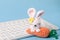 . Knitted Easter bunny on a blue background with a keyboard. Happy easter. Blank for Easter greetings for people whose profession