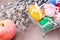 Knitted Easter eggs tied with colored ribbons in a metal basket, an apple and willow