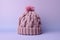 Knitted hat with bobble on pastel violet background