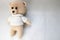 A knitted homemade beautiful cute little bear in a white sweater with black eyes, a soft toy tied with beige large threads on a li