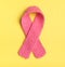 Knitted Pink Womens Breast Cancer Symbol in center on yellow background with room or space on sides for copy, text, or your words.