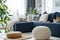 Knitted poufs near dark blue corner sofa. Scandinavian home interior design of modern living room