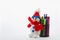 Knitted snowman, as the main symbol of winter, rests on cup with multi-colored markers on a light background