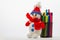 Knitted snowman, as the main symbol of winter, rests on cup with multi-colored markers on a light background