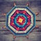 Knitted tibetan mandala from threads on wooden background