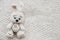 A knitted white bear is lying on a light knitted handmade fabric