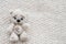 A knitted white bear is lying on a light knitted handmade fabric