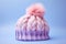 Knitted winter hat with bobble on pastel violet background