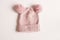 Knitted woolen hat of pink color with pompoms on white background