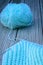 Knitting needles crossed over knitwork in progress. Baby blue arrangement on wooden background. Concept of craft and creativity