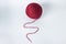 The knitting thread is unwound from a ball. A thread of burgundy color.