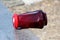 Knocked over dark red graveyard candle positioned on edge of marble tombstone