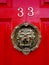 Knocker on red door number 33 with animal face