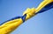 Knot on a stretched blue and yellow Ukrainian flag against the sky. Stand with Ukraine