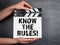 KNOW THE RULES. Business background. Movie clapper in woman hand. Black chalk board background